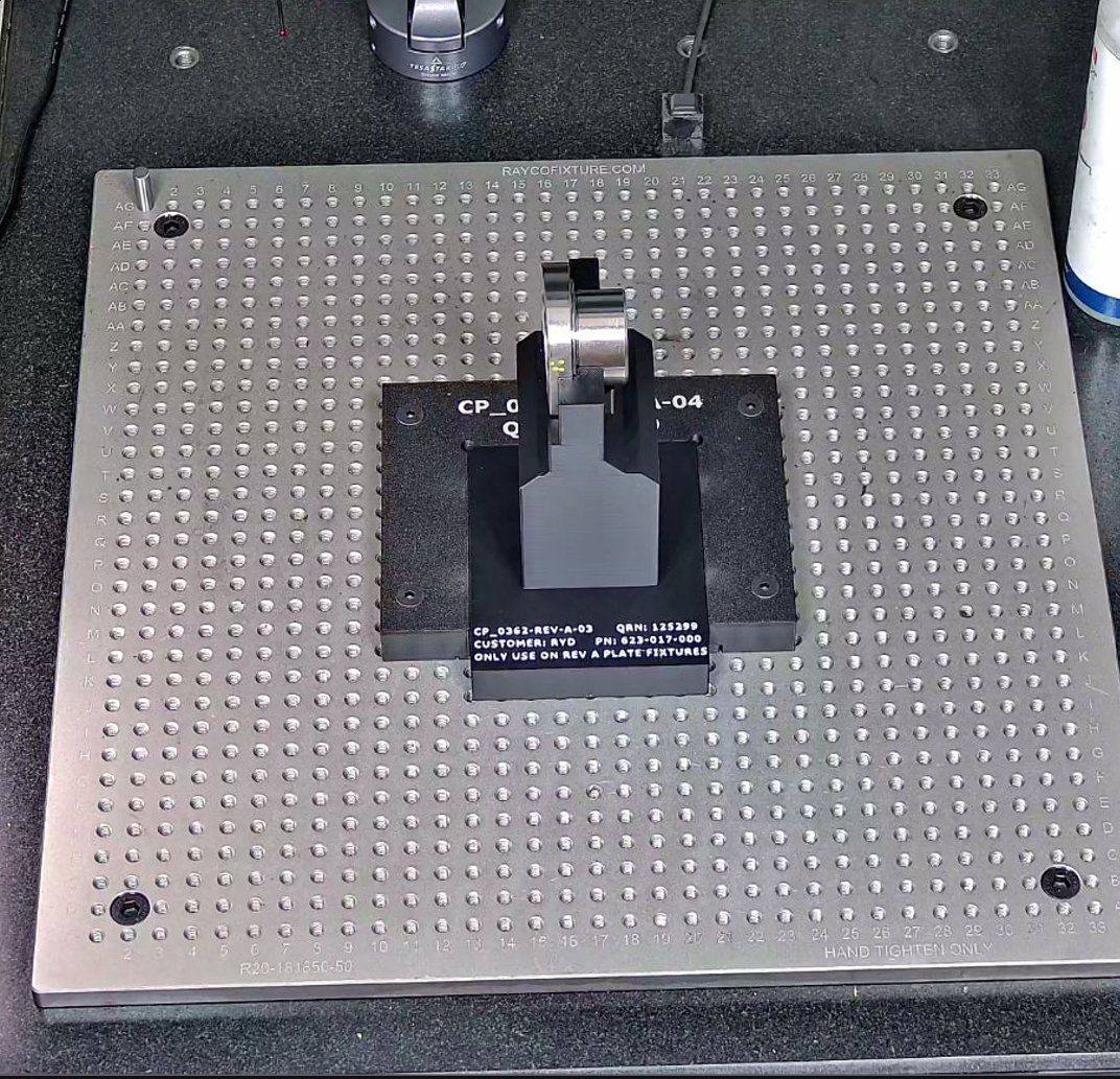 3D-printed fixture with engraved revision and part number holding a part on a CMM granite plate