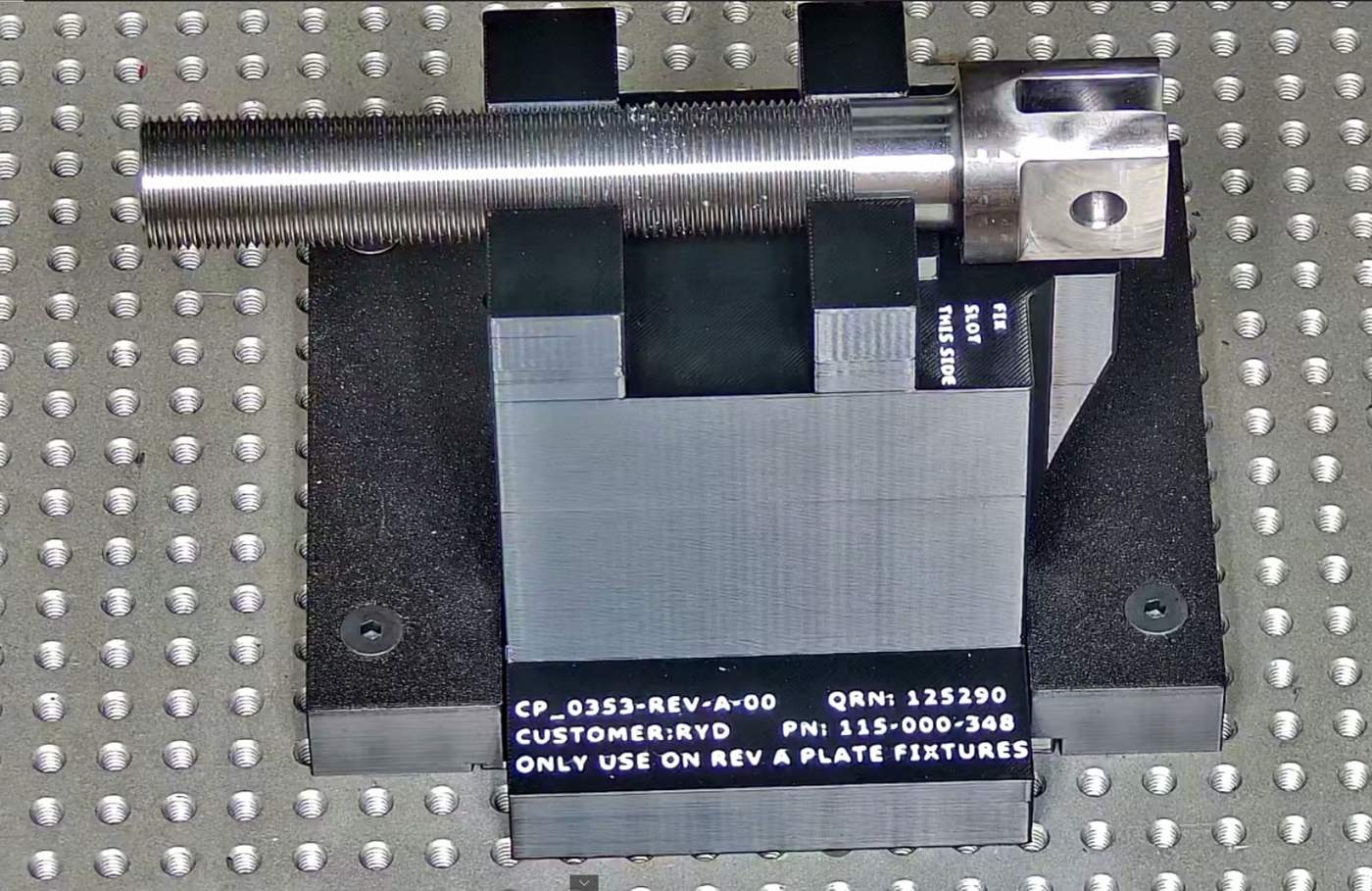Threaded shaft held in a labeled, revision-controlled 3D-printed fixture on a CMM plate